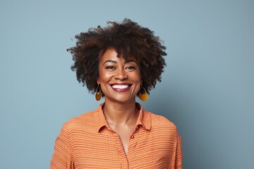 Wall Mural - Portrait of a joyful afro-american woman in her 40s smiling at the camera in blank studio backdrop