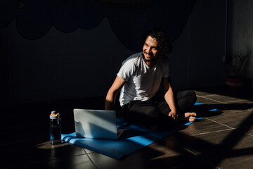 Wall Mural - Young latin man practicing yoga and fitness with online training on laptop at home in Mexico Latin America, hispanic people	