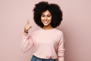 Wall Mural - Portrait of a glad afro-american woman in her 20s showing a thumb up while standing against blank studio backdrop