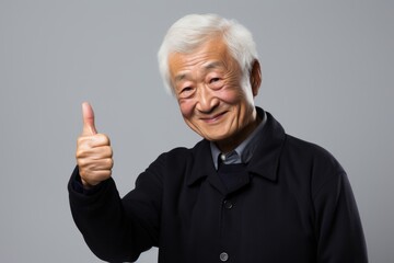 Wall Mural - Portrait of a tender asian elderly man in his 90s showing a thumb up in front of light wood minimalistic setup