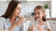 © Dina Photo Stories - Young beautiful mother and little girl drinking fresh pure water from glasses in kitchen Happy mom and daughter holding glasses with water. Eating habits, water filter advertisement, healthy nutrition