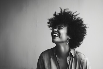 Wall Mural - Portrait of a happy afro-american woman in her 40s laughing isolated on bare monochromatic room
