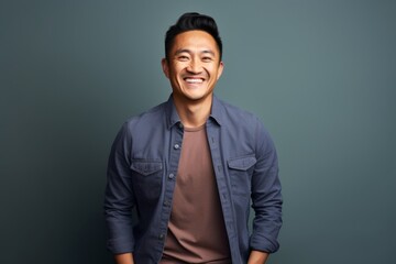 Wall Mural - Portrait of a joyful asian man in his 30s smiling at the camera isolated on plain cyclorama studio wall