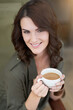 © peopleimages.com - Woman, relax and portrait with tea in cafe with happiness in calm morning schedule. Girl, face and drink latte at coffee shop with smile or enjoy hot chocolate from small business and restaurant