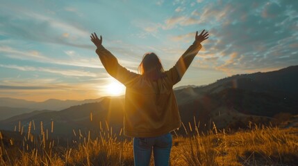 The girl on the top of the mountain raised both hands, the sun was setting. concept of success and achievement, joy, happiness.