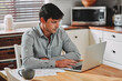 © peopleimages.com - Laptop, documents and businessman with coffee in kitchen reading email or online communication. Paperwork, computer and professional male hr freelancer work on startup company policy review at home.