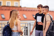 © Dasha Petrenko - Four teenagers in casual clothes chat and laugh on the roof of the house