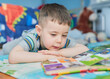 © Klarion - young boy reading a book with animal pictures