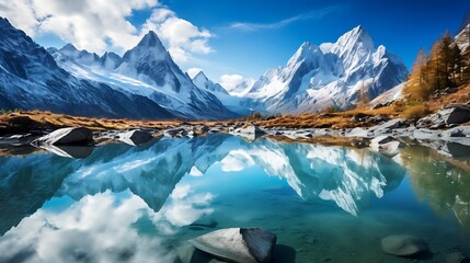 Mountain landscape with a crystal-clear lake reflecting snowy peaks under a blue sky