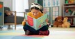 © peopleimages.com - Girl, school and reading book in classroom, childhood development and growth for vocabulary in kindergarten. Happy, smile and knowledge or information with storybook, learning and fantasy for child