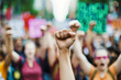 © forenna - raised fists of protestors, symbolizing strength and resistance. The image is taken from a low angle, emphasizing the unity and resolve of the crowd. Behind the fists, blurred yet