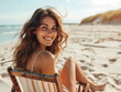 © JMDuran Photography - Happy smiling pretty young woman sitting on a deck chair on a sandy beach on a sunny day during summer holiday.