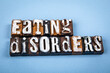 © STOATPHOTO - EATING DISORDERS. Wooden alphabet letter blocks on blue textured background