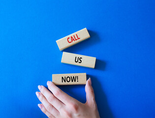 Canvas Print - Call us now symbol. Wooden blocks with words Call us now. Beautiful blue background. Businessman hand. Business and Call us now concept. Copy space.