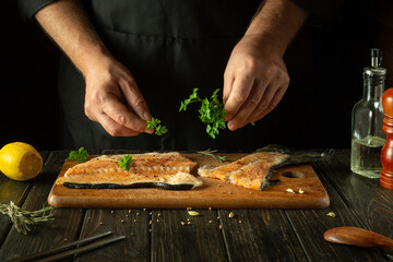 Wall Mural - The chef prepares fresh red fish on the kitchen table in the hotel. Before frying, fish steaks are seasoned with aromatic herbs. Asian cuisine.