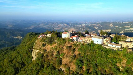 Wall Mural - Smooth aerial push-in shot from Smerillo (Fermo) with the manyfold white and beige buildings of the village sitting on a lone mountainous cliff almost suspended among vast visuals of Marche hillscapes