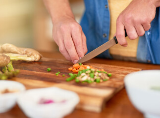 Wall Mural - Vegetables, chopping and hand with knife, kitchen counter and cooking for dinner on wood board. House, meal prep and person with carrot for nutrition, healthy food and organic for vegan and closeup