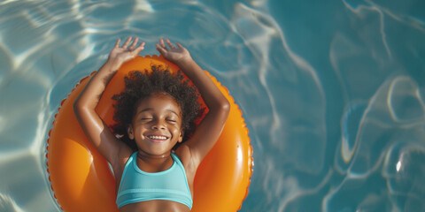 Wall Mural - Aerial view of a happy girl with curly hair lying on an orange float in a light blue pool, the girl smiles and enjoys a sunny day outdoors.