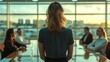 © K-MookPan - Businesswoman facing meeting with colleagues in an office with city skyline view.