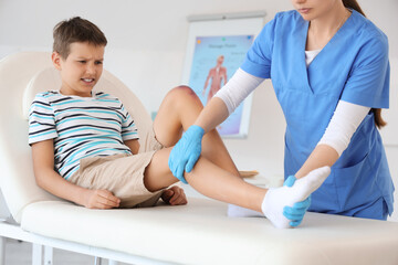 Wall Mural - Little boy with injured leg visiting doctor in clinic