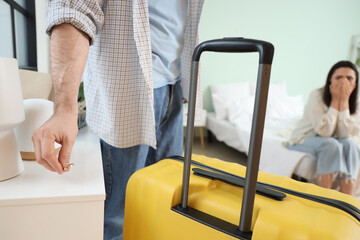 Canvas Print - Young man with suitcase putting his wedding ring on shelf in bedroom, closeup. Cheating concept