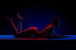 © Michael Rekochinsky - Beautiful young brunette woman lying in sexy lingerie in colored light in studio on a dark background