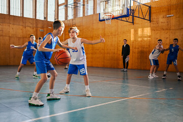 Wall Mural - Junior basketball team playing basket on training at indoor court.