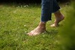 © New Africa - Woman walking barefoot on green grass outdoors, closeup