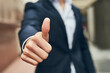 © peopleimages.com - Businessman, hand and review with thumbs up in city for vote, winning or business success. Closeup of man or employee with like emoji, yes sign or OK in approval or positive feedback in an urban town