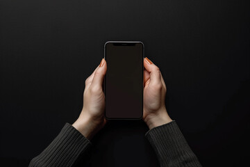 Wall Mural - A person's hands, with refined and articulate fingers, holding a blank mobile screen mockup against a stark black background.