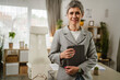 © Miljan Živković - Portrait of mature caucasian woman stand and hold tablet at office