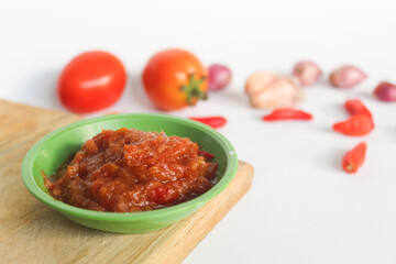 Portrait of tomato chili sauce in a green bowl isolated on a white background, seasoned with tomatoes, chilies, shallots, garlic.