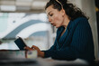 © qunica.com - Young businesswoman looking surprised while checking her phone in an office setting. A candid moment showcasing a reaction to unexpected news or information at work.