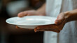 © mohammad - hand holding an empty white plate, the details of the fingers holding the plate and the clean surface of the plate are clearly visible. Ai generated Images