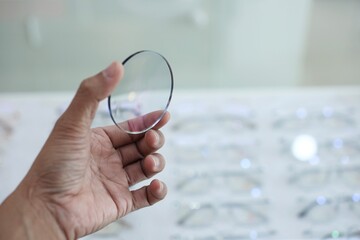 Sticker - close up of hand holding glassesl lenses in optical store 