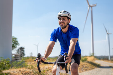 Caucasian active sportsman riding bicycle at the wind turbine field. 