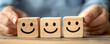 © alexandre - A person holding wooden blocks with smile face for positive customer review satisfaction feedback rating.