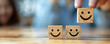 © alexandre - A person holding wooden blocks with smile face for positive customer review satisfaction feedback rating.