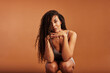 © Flamingo Images - Young black woman crouching in underwear against an orange background