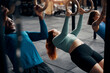 © Flamingo Images - Young woman working out with friends on rings during a gym class
