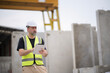 © Wanwajee - Senior White engineer holding tablet looking away with serious emotion at work site. Portrait og engineer wearing white hard hat at manufactuing.