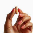 © Shafag - Hand holding a pill between thumb and forefinger isolated on white background. Made with generative ai
