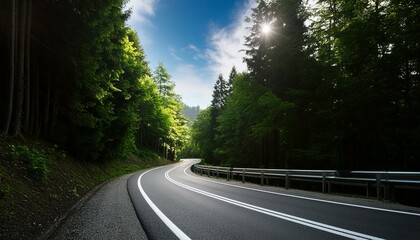 Poster - A scenic asphalt road winding through a lush forest of vibrant green trees, the azure sky stretching overhead