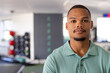 © Wavebreak Media - At gym rehabilitation center, young biracial male physical therapist wearing a green polo shirt stan