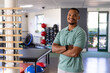 © Wavebreak Media - A biracial male physical therapist standing in gym rehabilitation center, arms crossed