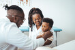 © Dragana Gordic - Smiling male pediatrician in white medical uniform holding clipboard, listening to young mother with kid son at checkup meeting, professional children doctor consultation, healthcare concept.