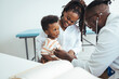 © Dragana Gordic - Shot of a single mother bringing his little boy for a checkup. Happy multiracial family visiting clinic for check up. Kind male pediatrician smiles as he talks with an adorable baby boy.