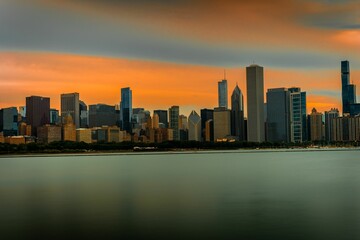 Wall Mural - Scenic view of a cityscape against the sea at orange sunset