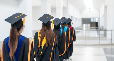 Wall Mural - A group of women in graduation gowns are walking down a hallway