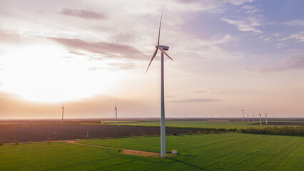 Wall Mural - renewable eco energy on sunset green field.Close up high wind turbine generation electricity